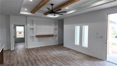 Unfurnished living room featuring beam ceiling, hardwood / wood-style flooring, and ceiling fan | Image 3