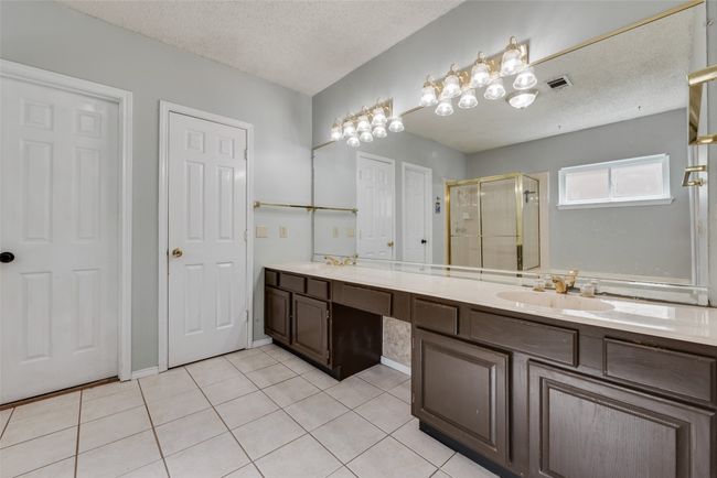 Bathroom featuring a shower stall, double vanity, tile patterned floors, and a textured ceiling | Image 17