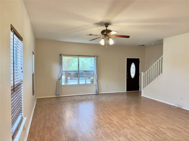 Unfurnished living room featuring healthy amount of natural light, a ceiling fan, wood finished floors, and stairway | Image 12