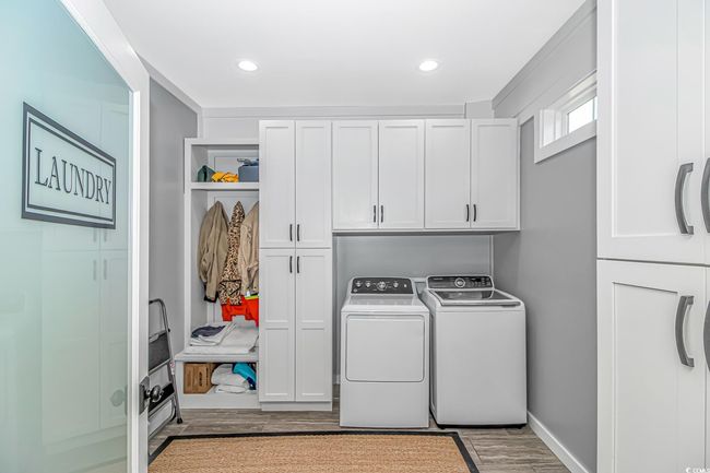 Washroom featuring cabinet space, washing machine and dryer, wood finished floors, and recessed lighting | Image 12