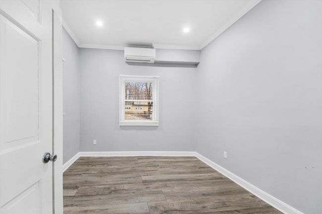 Spare room with a wall unit AC, wood finished floors, ornamental molding, baseboards, and recessed lighting | Image 11