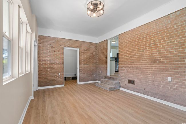 Spare room featuring light wood-style floors and brick wall | Image 11