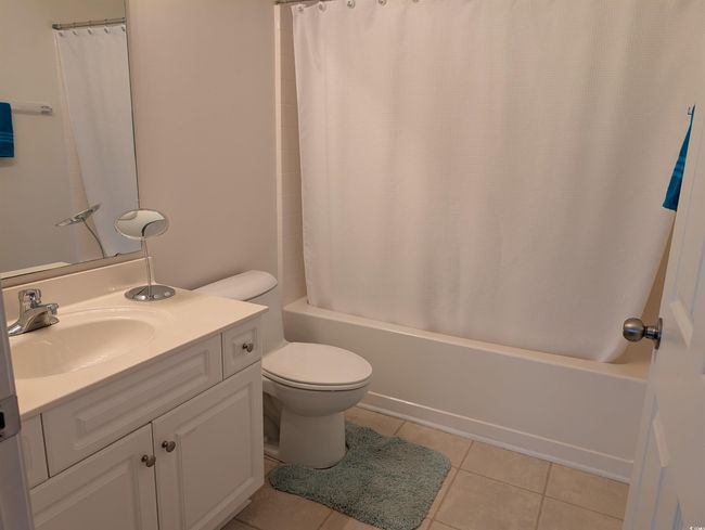 Full bathroom featuring tile patterned floors, toilet, vanity, and shower / bathtub combination with curtain | Image 15