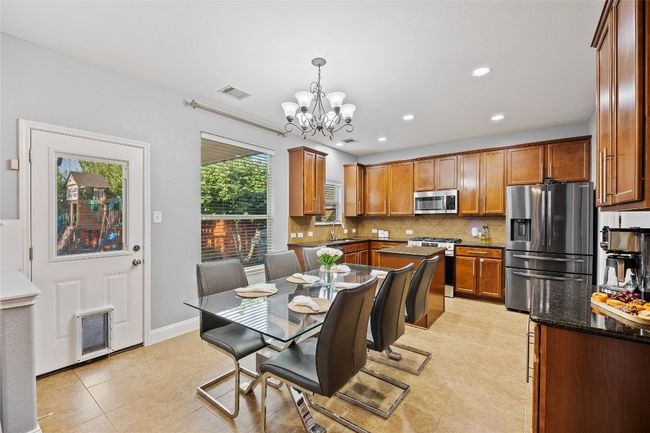 Dining space featuring a chandelier, light tile patterned flooring, and recessed lighting | Image 8