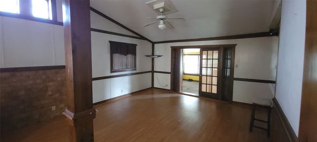 Spare room with a ceiling fan, wood finished floors, lofted ceiling, and a wainscoted wall | Image 6