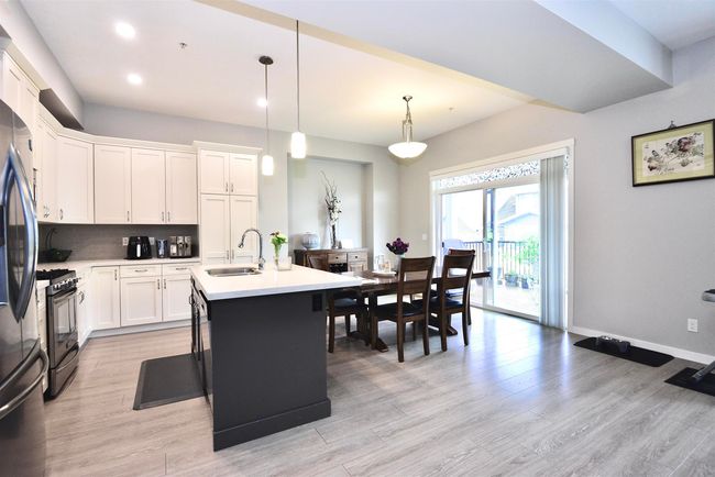Kitchen with black gas stove, light wood finished floors, decorative backsplash, light countertops, and recessed lighting | Image 18