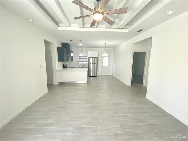 Unfurnished living room featuring ceiling fan and baseboards | Image 4