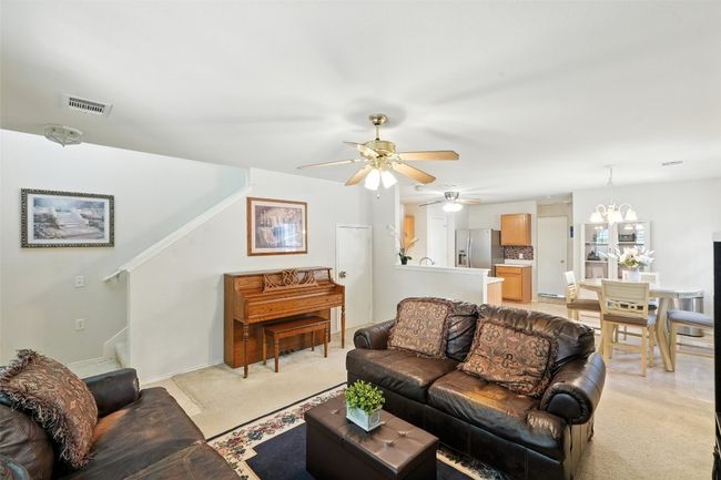 Living area featuring a ceiling fan, light colored carpet, and a chandelier | Image 6