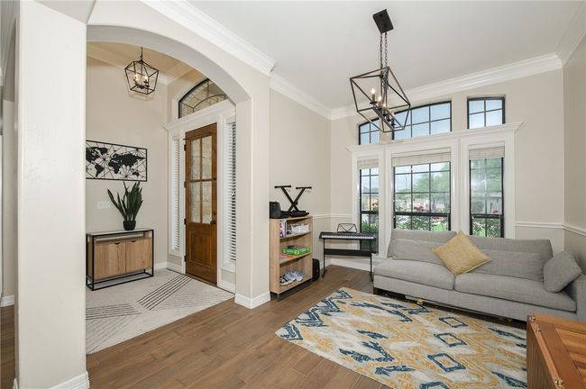 Foyer entrance with ornamental molding, a wealth of natural light, wood finished floors, and a chandelier | Image 8