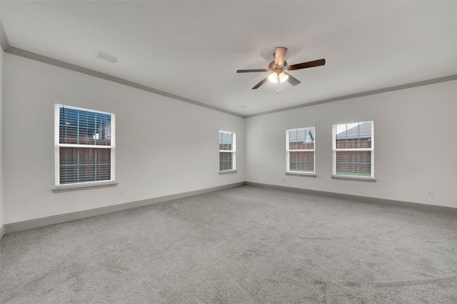 Carpeted empty room with ornamental molding, baseboards, a ceiling fan, and visible vents | Image 20