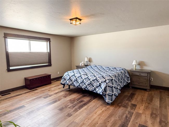 Bedroom with baseboards, a textured ceiling, visible vents, and wood finished floors | Image 14