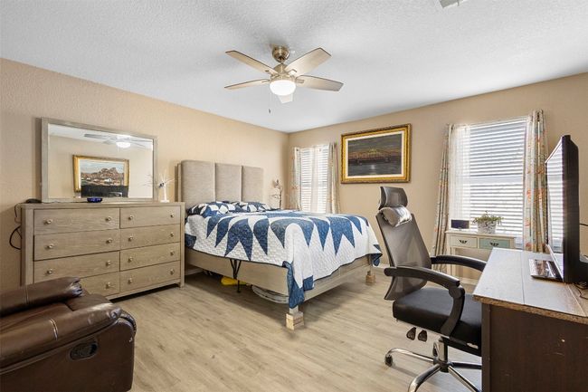 Bedroom with multiple windows, light wood-style floors, and a textured ceiling | Image 23