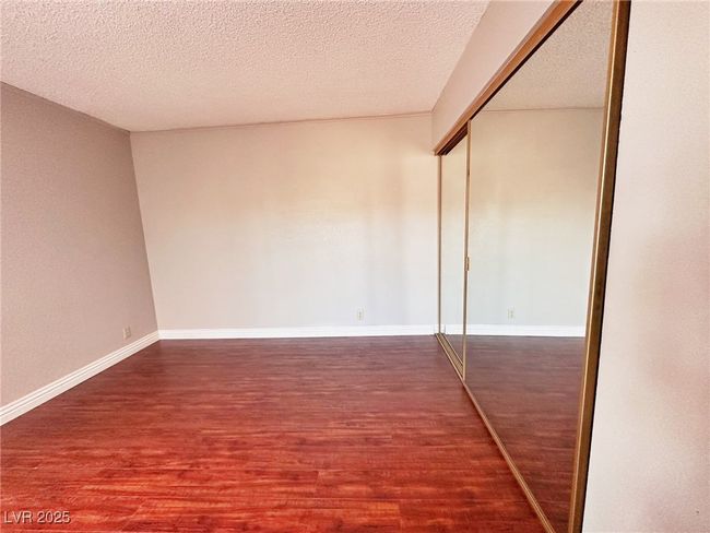 Unfurnished bedroom featuring wood finished floors, a closet, baseboards, and a textured ceiling | Image 12
