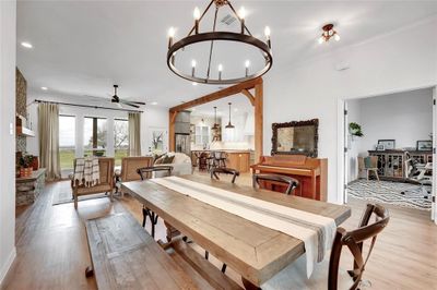 Dining room with crown molding, light wood-type flooring, and ceiling fan with notable chandelier | Image 3