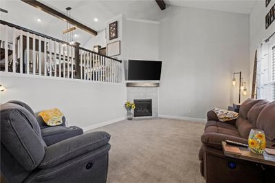 Living room with carpet flooring, beamed ceiling, high vaulted ceiling, and a fireplace | Image 3