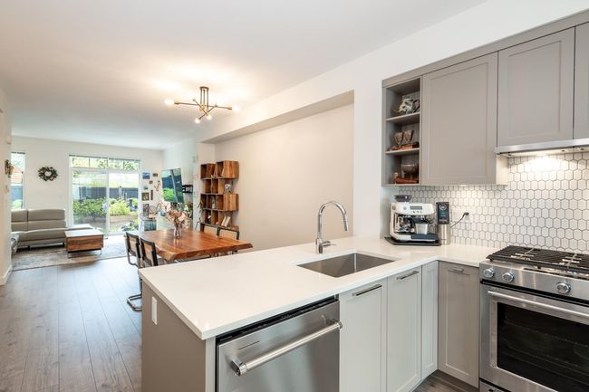Kitchen featuring stainless steel appliances, a sink, gray cabinetry, open shelves, and a peninsula | Image 7
