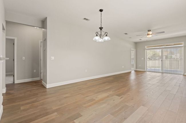 Spare room with baseboards, visible vents, light wood-style flooring, and ceiling fan with notable chandelier | Image 11