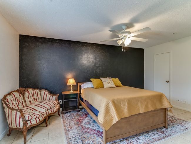 Bedroom featuring light tile patterned floors, a textured ceiling, a ceiling fan, and an accent wall | Image 22