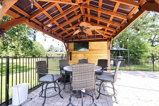 View of patio with a gazebo, outdoor dining area, and ceiling fan | Image 29