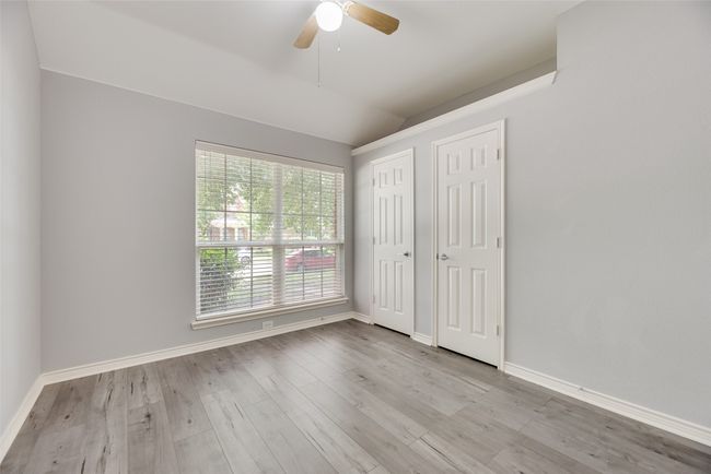 Unfurnished bedroom featuring lofted ceiling, wood finished floors, two closets, baseboards, and a ceiling fan | Image 13