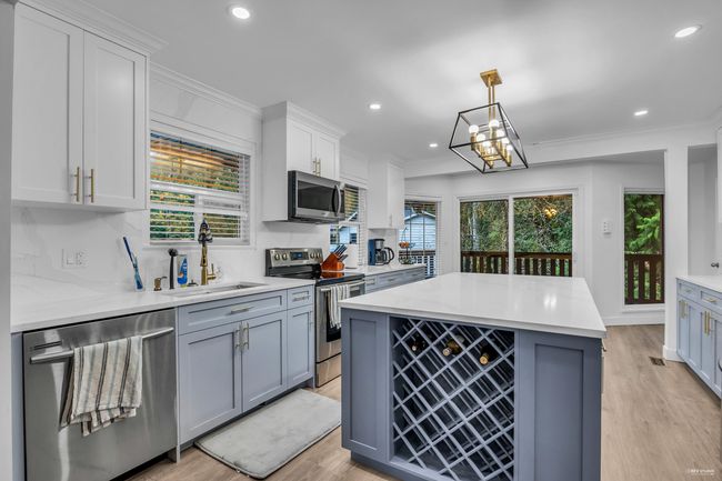 Kitchen featuring appliances with stainless steel finishes, light wood-style flooring, light countertops, recessed lighting, and white cabinetry | Image 13