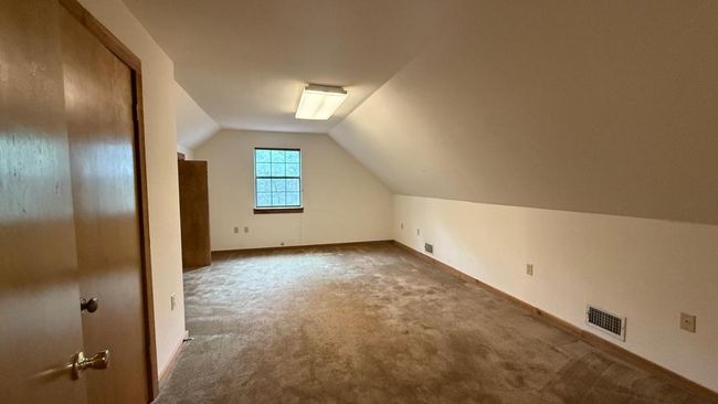 Additional living space featuring baseboards, visible vents, dark carpet, and lofted ceiling | Image 17
