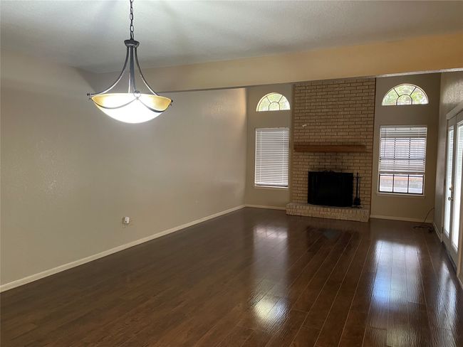 Unfurnished living room with healthy amount of natural light, baseboards, a brick fireplace, and dark wood-style flooring | Image 16