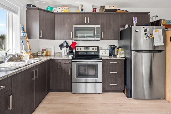 Kitchen with stainless steel appliances, dark brown cabinetry, and light wood finished floors | Image 44