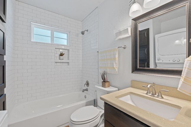 Full bathroom featuring estacked washer and dryer, vanity, bathtub / shower combination, and a textured wall | Image 32