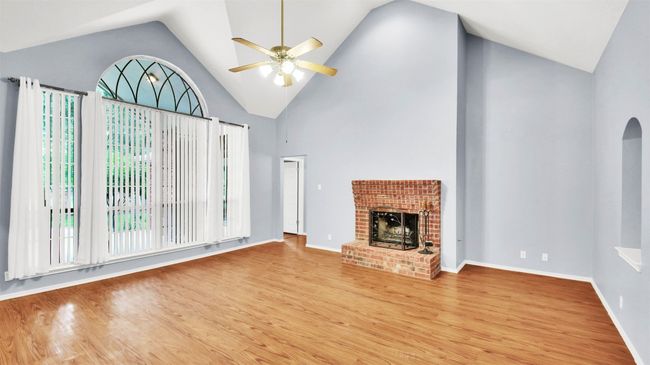Massive Livving room with ceiling fan, vinyl plank floors, a brick fireplace, and high vaulted ceiling | Image 9