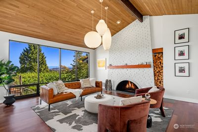 Stunning living room with vaulted ceiling, Herman Miller light fixtures, striking floor-to-ceiling fireplace, and expansive windows framing the view. | Image 3