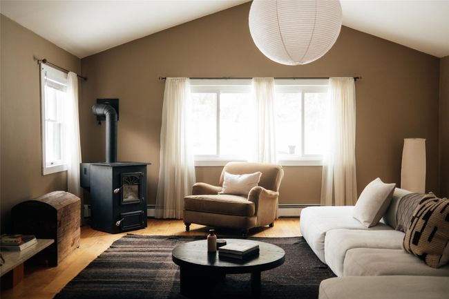 Living room with a healthy amount of sunlight, light hardwood / wood-style floors, vaulted ceiling, and a wood stove | Image 5