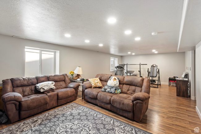 Living room featuring a textured ceiling, baseboards, wood finished floors, and recessed lighting | Image 19