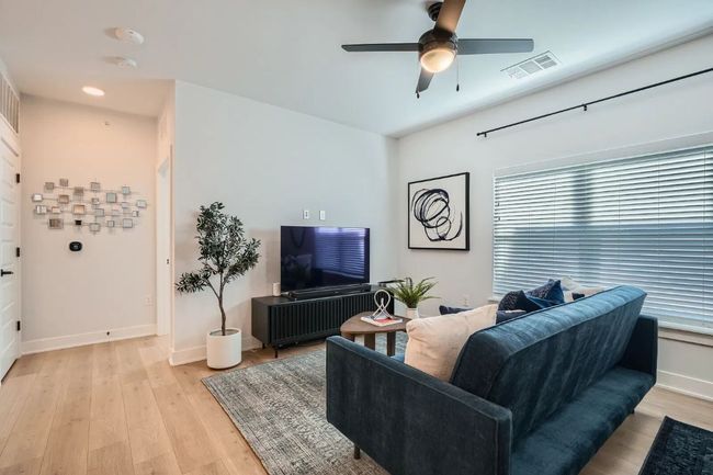 Living area featuring healthy amount of natural light, a ceiling fan, and light wood-style floors | Image 9