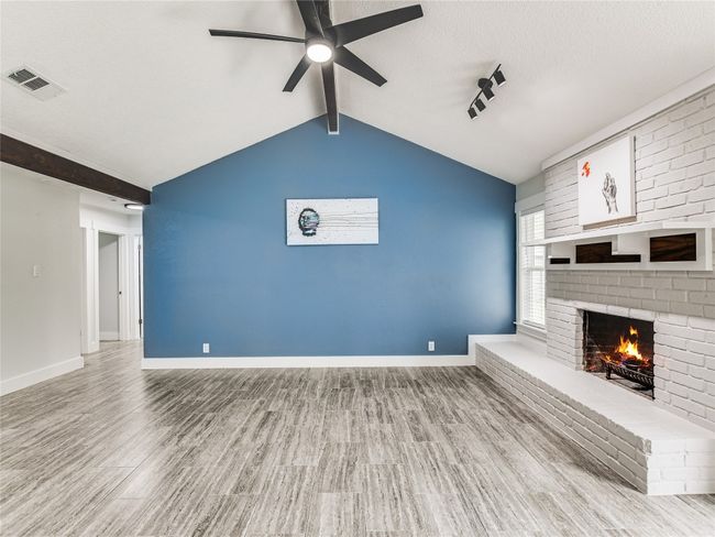 Unfurnished living room featuring wood finished floors, visible vents, a fireplace, ceiling fan, and baseboards | Image 4