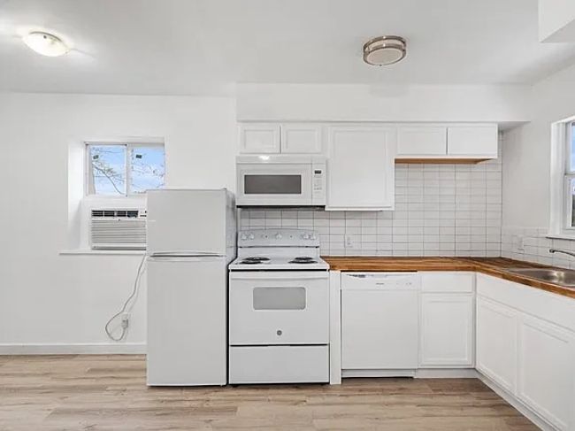 Kitchen featuring white appliances, white cabinetry, and decorative backsplash | Image 13