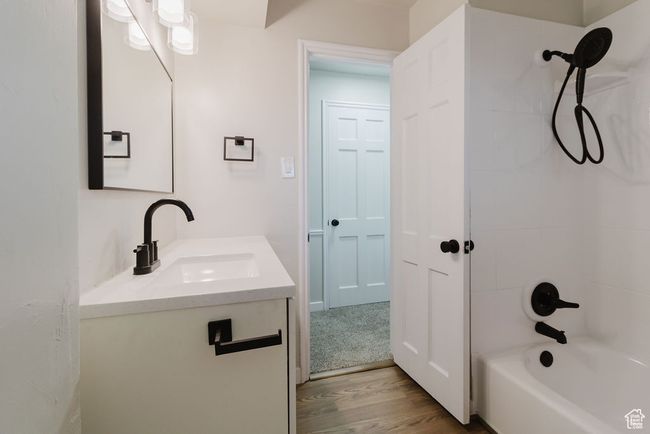 Bathroom featuring bathtub / shower combination, wood finished floors, and vanity | Image 15