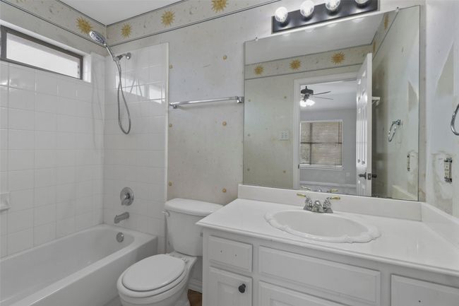 Full bath featuring tub / shower combination, vanity, ceiling fan, and wallpapered walls | Image 28