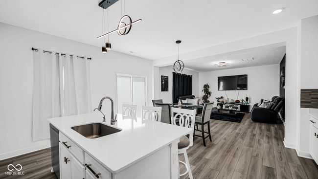 kitchen featuring a sink, dishwasher, open floor plan, wood finished floors, and white cabinets | Image 18