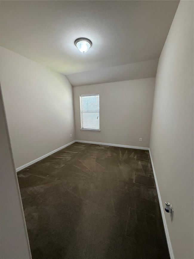 Unfurnished room featuring vaulted ceiling, baseboards, and dark carpet | Image 16