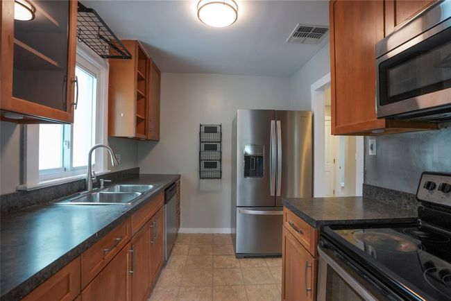 Kitchen with stainless steel appliances, a sink, dark countertops, baseboards, and visible vents | Image 12