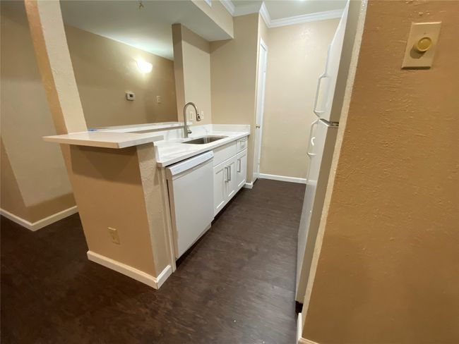Kitchen featuring crown molding, a sink, baseboards, white appliances, and a peninsula | Image 9