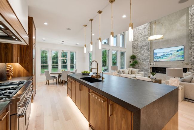 Kitchen with dark countertops, custom range hood, a sink, open floor plan, and light wood-type flooring | Image 9