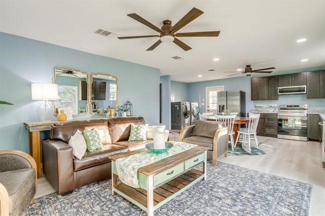 Living area featuring light wood-style floors, visible vents, ceiling fan, and washer and clothes dryer | Image 18