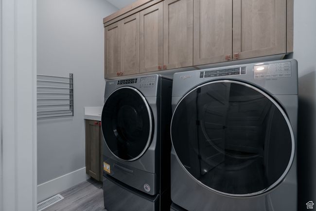 Washroom with cabinet space, washing machine and dryer, light wood-style floors, and baseboards | Image 27