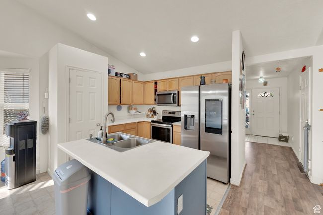 Kitchen with appliances with stainless steel finishes, vaulted ceiling, light brown cabinets, light countertops, and recessed lighting | Image 7