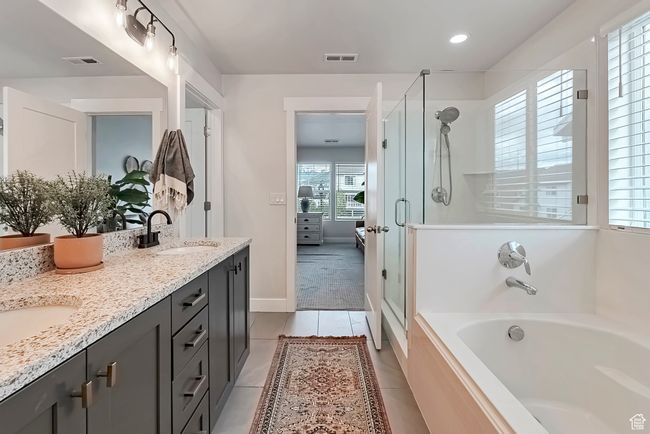 Ensuite bathroom with a stall shower, double vanity, a garden tub, tile patterned flooring, and baseboards | Image 16