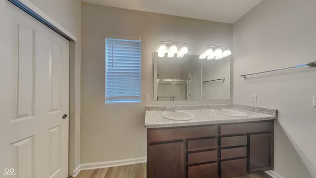 full bathroom featuring a stall shower, wood finished floors, double vanity, and a sink | Image 9