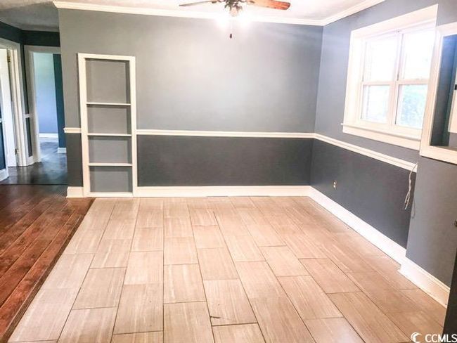 Unfurnished bedroom with a wainscoted wall, a textured ceiling, wood-type flooring, ornamental molding, and a closet | Image 10