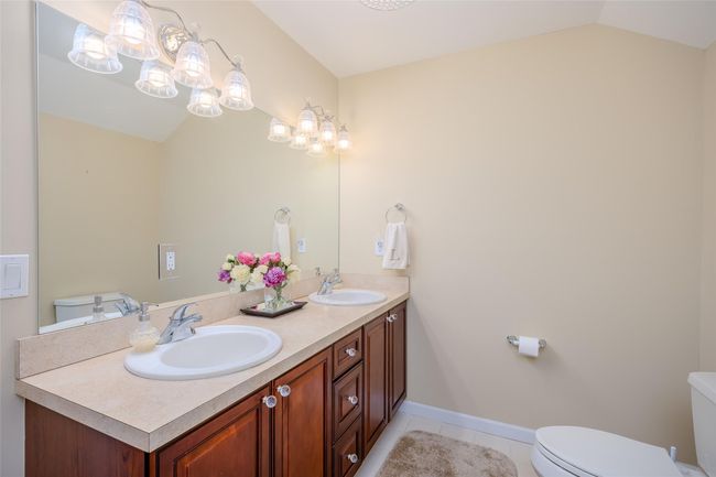Bathroom with tile patterned flooring, double vanity, and lofted ceiling | Image 24